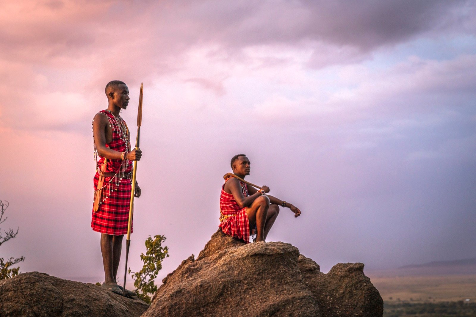 Two Maasai warriors on the rocks at dusk